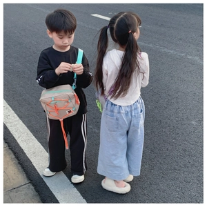 Detail of khaki kids crossbody bag with orange drawstring and bear patch on a casual outfit