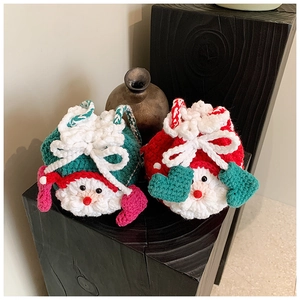 Detail of handmade crochet Christmas drawstring bags with 3D Santa Claus figure on wood