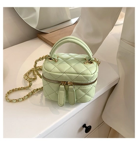 Detail of light green quilted mini bag with gold chain strap and dual zipper closure