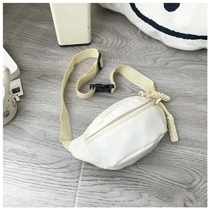 Detail of cream canvas waist bag featuring woven zipper pulls and adjustable strap