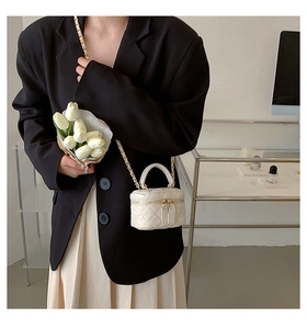 Close-up of white quilted mini crossbody bag with gold chain and dual zipper details