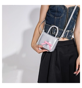 Micro silver crossbody bag with pink bow showing scale and Y2K metallic texture