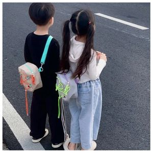Detailed outdoor view of kids' fashion crossbody bags with vibrant drawstring accents