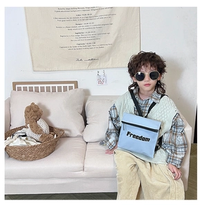 Close-up of light blue kids' Freedom crossbody bag on a child model in a cozy setting