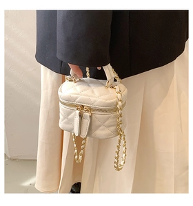 Detailed view of cream quilted mini vanity bag with gold chain strap on model