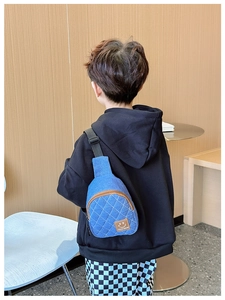 Dettaglio del borsello monospalla in denim blu per bambini con ricami a rombi e patch