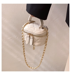 Close-up of white quilted mini cosmetic box bag with gold chain strap and top handle