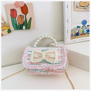 Detail of pink and green tweed bag with large pearl bow and elegant lace trim