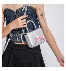Detail view of silver metallic mini bag with a pink bow and a polished mirror finish