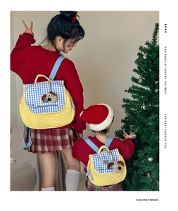 Detail of yellow quilted parent-child backpacks featuring blue checkered flaps and cute puppy