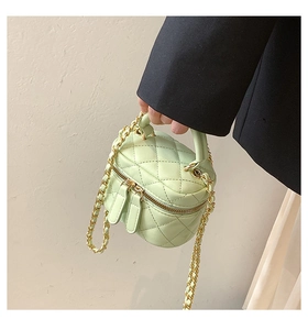 Detail of mint green quilted leather mini vanity case with gold chain strap held by model