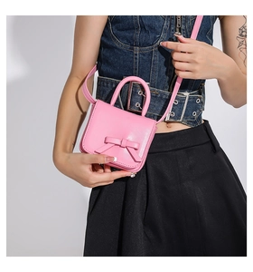 Detailed view of mini pink crossbody bag with a 3D bow on a high-quality leather surface