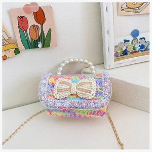 Close-up of pink tweed mini bag featuring a pearl bow detail and elegant gold chain strap