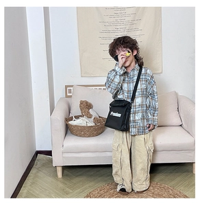 Kids streetwear detail showing a plaid shirt, corduroy pants, and black Freedom crossbody bag