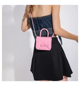 Detail of pink mini crossbody bag featuring a sweet bow and leather top handle decoration