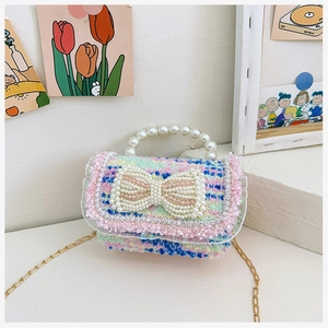 Close-up of a tweed mini bag with oversized pearl bow and pink fringe details