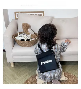 Close-up of a child wearing a black canvas backpack with white Freedom letter print