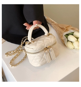 Detail of white quilted mini bucket bag with gold chain strap and double zipper