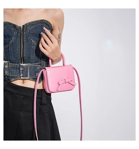 Detailed side view of pink crossbody bag featuring a 3D bow design on a model