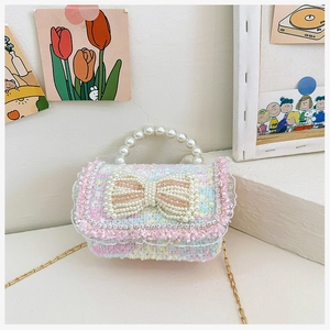 Detail of pink tweed mini bag with pearl handle, bow decoration and gold chain strap