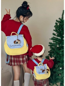 Detail of quilted yellow kids backpack with cute 3D bear and blue checkered flap