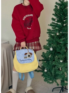 Detail of yellow quilted backpack with blue plaid flap and plush puppy dog decoration