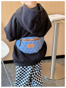 Dettaglio del marsupio in denim trapuntato per bambini con toppa in pelle arancione