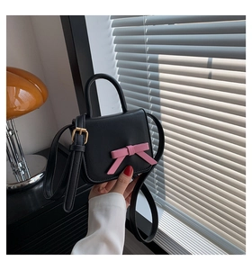 Detailed macro view of a mini black and pink crossbody bag with a 3D bow and gold buckle
