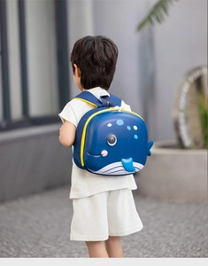 Rear view of a child wearing a 3D blue whale cartoon EVA hardshell backpack outdoors