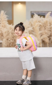 Pink and yellow cartoon whale EVA hard shell backpack worn by a child in a studio setting
