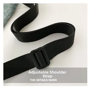 Détail de la bandoulière réglable en nylon noir avec boucle sur un sac en toile