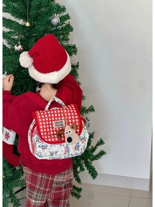 Detail of quilted kids backpack with red plaid cover and cute puppy plush pendant