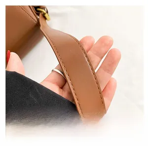 Detail of brown leather shoulder strap with durable stitching and brass hardware