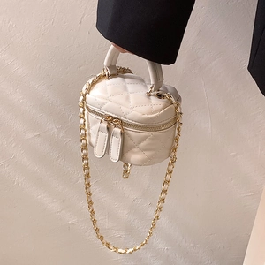 Mini white quilted leather handbag with gold chain strap held by a person in a black suit