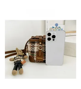 Detailed view of winter checkered bucket bag for kids with cute bunny charm and phone reference
