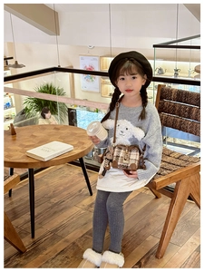 Close-up of kids brown quilted bucket bag with white plush lamb charm and fashion patch