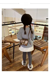 Girl wearing a brown plaid bucket bag with a cute rabbit pendant in a cozy cafe setting