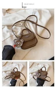 Dettaglio di una mini borsa a tracolla marrone da ragazza con manico e ciondolo a orso