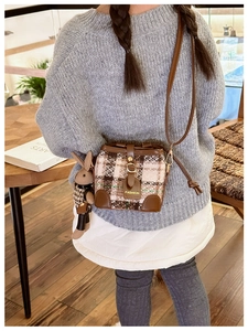 Close-up of a brown quilted leather bucket bag with a cute 3D bunny plush pendant