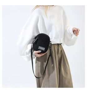Détail d'un petit sac en velours côtelé noir avec fermeture éclair et étiquette Fashion