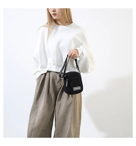 Détail du sac bandoulière en velours côtelé noir avec étiquette FASHION et sangle nylon
