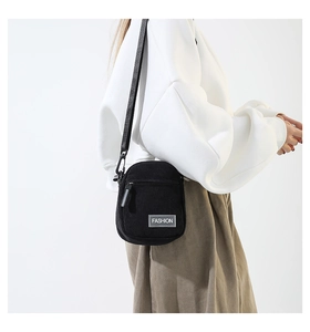 Vue latérale d'un mini sac bandoulière en velours côtelé noir porté par un mannequin