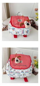 Detail of red checkered quilted kid backpack with cartoon print and plush dog charm