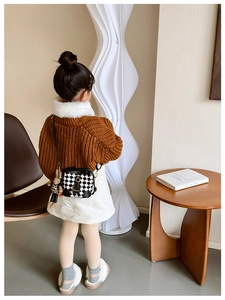 Detailed back view of a girl wearing a checkerboard crossbody bag with a plush bunny charm