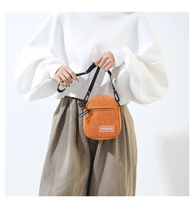 Détail de la mini sacoche en velours côtelé orange vif avec étiquette tendance