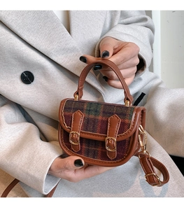 Gros plan d'un mini sac à main vintage à carreaux avec sangles en cuir marron