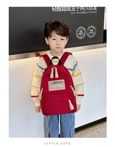 Petit garçon asiatique portant un sac à dos rouge en toile avec écusson FASHION