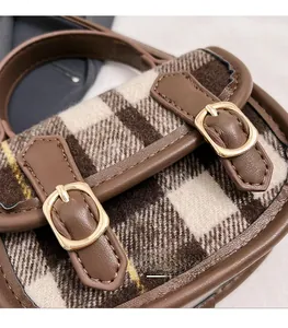 Détail du tissu en laine à carreaux marron avec garniture en cuir et boucle dorée chic
