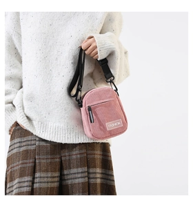 Détail du sac bandoulière en velours côtelé rose avec étiquette Fashion et sangle réglable