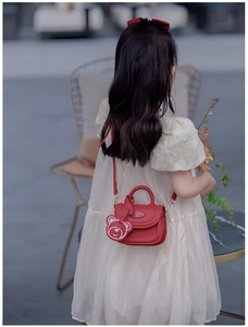 Vista posteriore di una mini borsa rossa per bambini con un grazioso ciondolo a orsetto